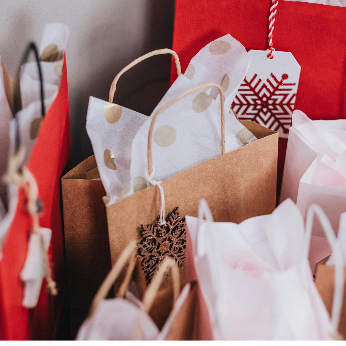 Holiday gift bags in white, red, and brown craft paper, including tags with snowflakes.