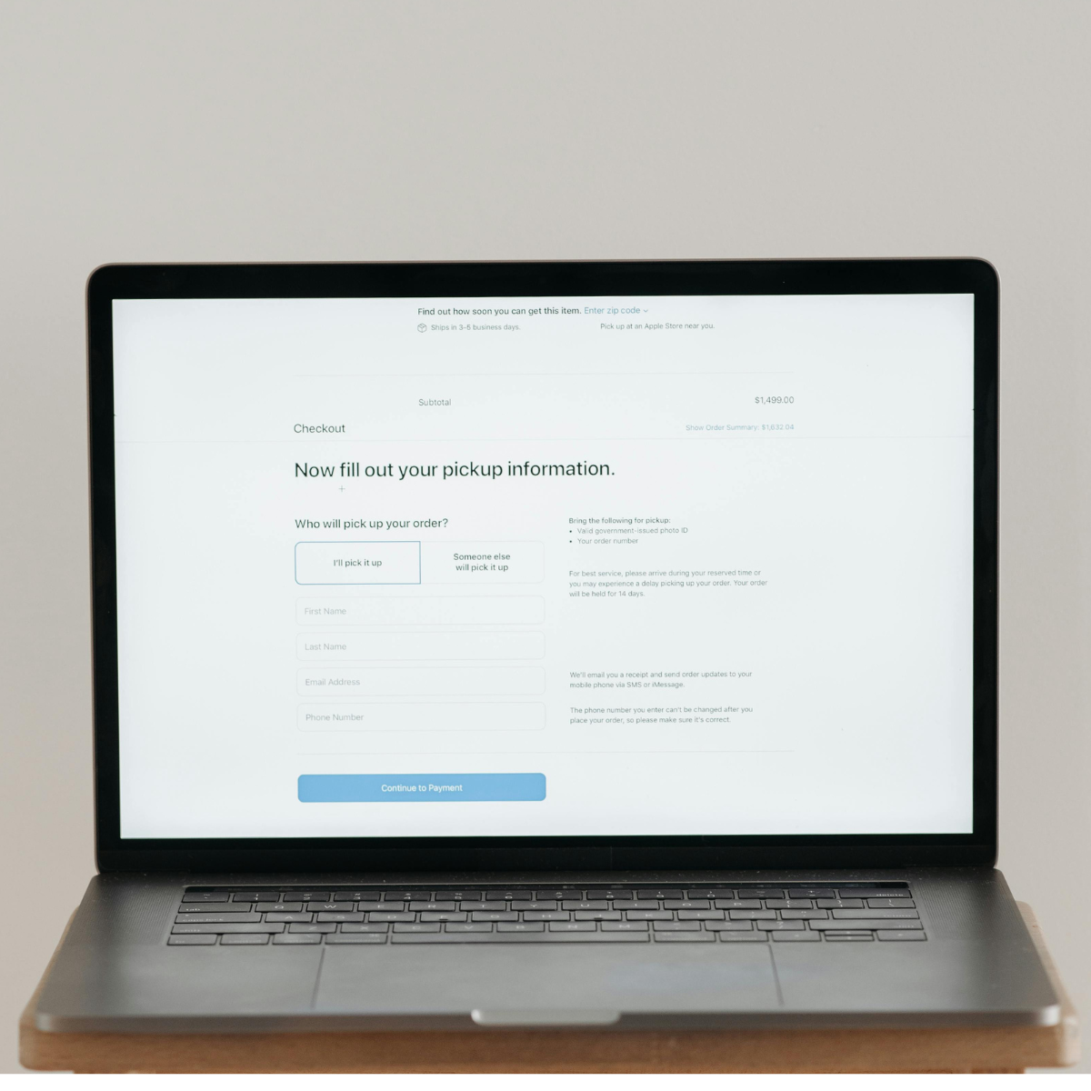 Laptop rests on small wooden table and there's a form on the screen.